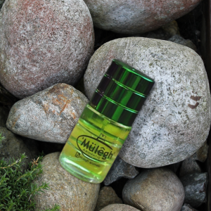 botol parfum mulegh warna hijau di atas batu batu kecil